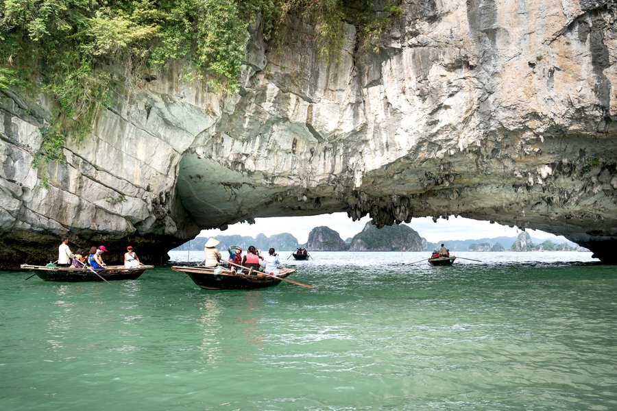 Rowing boat passing through the arch of Luon Cave, Ha Long Bay